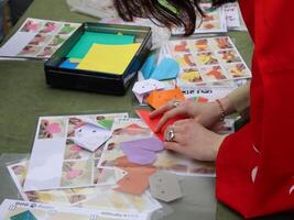 Hands Folding Origami Figures at a Workshop. Close-up of hands carefully folding origami, likely at a community workshop or craft fair photo
