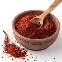 A rustic, round clay bowl filled with finely ground red chili powder. The deep red hue of the spice contrasts with the earthy texture of the bowl photo