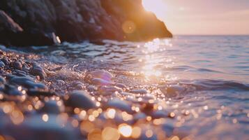 Gentle waves create ripples over pebbles as the sun sets, casting a golden glow on the tranquil water photo