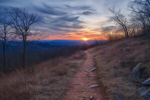 Sunset on mountain with trail leading up side. photo