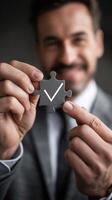 Business solution concept. Businessman holding jigsaw puzzle with check mark on it. Puzzle piece representing the right personnel. Business strategy analysis and plan. photo