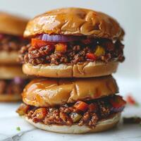 Three stacked beef burger sliders with various toppings including tomato, onion, and peppers. photo