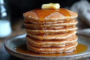 Stack of golden brown pancakes drizzled with syrup and topped with a pat of butter photo