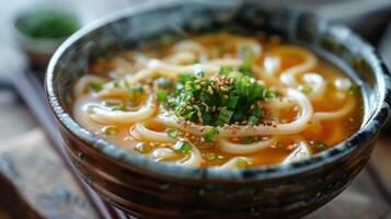 a bowl of soup with noodles and chopsticks on the table photo
