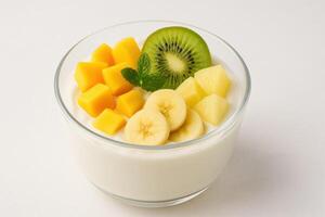 Bowl of creamy tropical greek yogurt topped with fresh mango, banana, pineapple, and kiwi slices, garnished with mint leaf photo