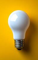Light bulb on vibrant yellow background. A clear light bulb rests on a bright yellow surface, showcasing its reflective surface and design. photo