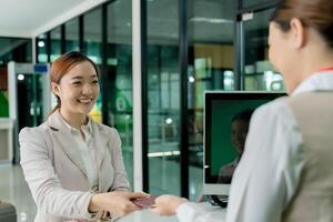 Happy woman handing over passport and boarding pass to airline staff at airport check-in counter with friendly service and smooth travel experience photo