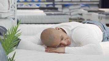 Young man testing a comfortable orthopedic mattress in a stylish furniture store video