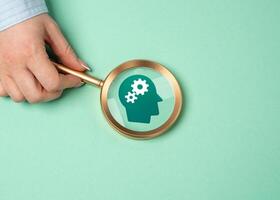 A magnifying glass points to the gears in a person's head. The concept of talent search and thinking development. Analyzing cognitive processes, discovering potential, intellectual growth. photo