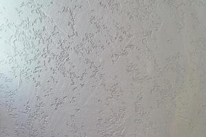 Uneven background with the texture of decorative plaster painted in white concrete wall. Rough wall with space for copying photo