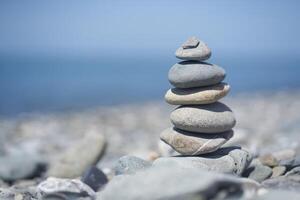 Balancing rocks on a pebble beach during sunset. Smooth pebbles on the beach against the background of the sea and sunlight, creating a side effect on the water photo