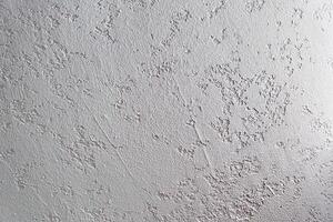 White plastered wall. Uneven background with the texture of decorative plaster painted in white concrete wall. Rough wall with space for copying photo