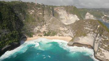 Aerial view of dramatic cliffs, turquoise waves, and hidden Kelingking beach on Nusa Penida island, Bali, Indonesia video
