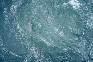 Blue water. Beautiful background with a place to copy. Close-up of raging waters. Ripples and waves on the water. photo