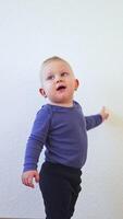 A little boy in a bodysuit runs around the room and laughs. The child has fun running around the house. video