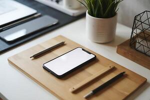 Minimalist workspace featuring mobile devices, pens, and greenery elements photo