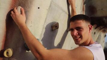 A man is climbing a wall with his hands on the wall. The man is enjoying the challenge video