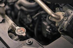 Close up of a vehicle coolant reservoir cap and surrounding engine components. Car engine radiator cap. photo