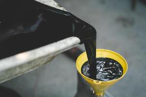 Old engine oil. Pouring old black oil of car engine from oil pan into bottle on top view lubrication used for recycle. photo