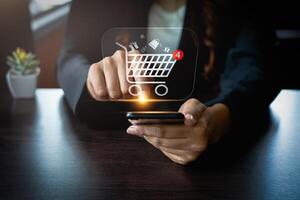 Woman Using Smartphone for Online Shopping with Virtual Shopping Cart Icon Showing New Notifications, Highlighting E-Commerce, Digital Transactions, Mobile Retail, and Consumer Convenience photo
