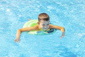 Funny happy child boy in swimming pool on inflatable rubber circle ring photo