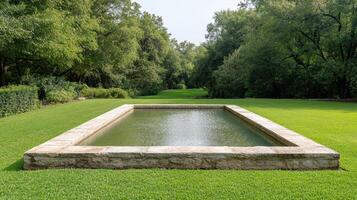 A large stone pool in the middle of a lush green field photo