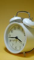 Time lapse of a white alarm clock on a yellow background video