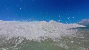 Slow motion captures an ocean wave crashing toward the camera with powerful sprays and foamy swirls, creating an immersive presence effect. The turbulent water energy video