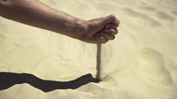 Slow-motion shot of male hand releasing yellow sand from clenched fist against desert backdrop. Powerful metaphor for desertification and climate change impacts. video