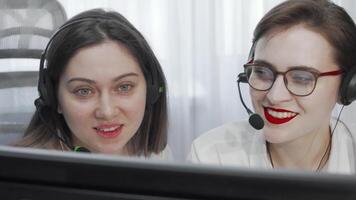 Engaged female call center operators collaborating with headsets and computers video