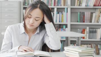 Exhausted Asian young woman dozing off while studying in the library video