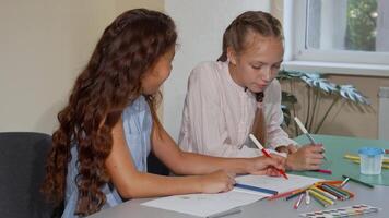 Two school friends joyfully chatting while creating colorful drawings in art class video