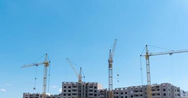 Time-lapse of a building under construction, and four large cranes moving together. video