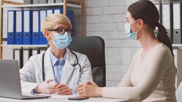A dietitian is advising a client on nutrition choices in a contemporary clinic setting. Both individuals are wearing masks, ensuring a safe environment during the consultation. video