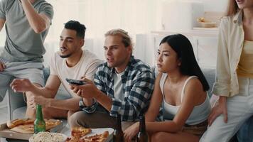 A group of diverse friends, including millennials, gather in a bright living room to share laughter, pizza, and drinks, enjoying quality time together in a relaxed atmosphere. video