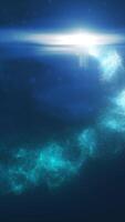 Blue glowing particles swirling through water-like textures in a dark, tranquil setting video