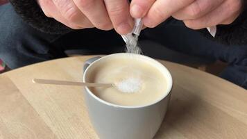 male hand mixes sugar in coffee on a wooden table. View from above. video