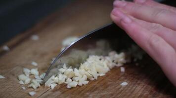 Front view of yong man cook cut thin slices of garlic with knife on cutting Board. Closeup shot with natural light video