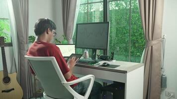 A man sitting at a desk with a computer and guitar video