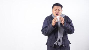 Sick man wearing jacket is suffering from flu and sneezing using tissue paper isolated on white background photo