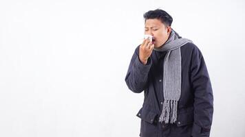 Unhealthy man wearing jacket blows his nose with tissue paper, suffering from flu isolated on white background photo