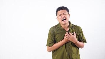 Young Asian man having heart ache, holding hand on chest due to heart attack or heart pain isolated on white background photo