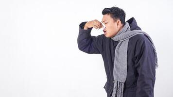 Sick man wearing jacket blows his nose with tissue paper, suffering from flu isolated on white background photo