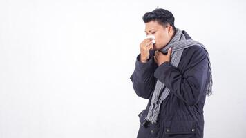 Portrait of sick man wearing jacket blows his nose with tissue paper, suffering from flu isolated on white background photo
