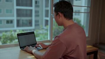 Focused Work from Home.A man sits at a desk by a window, intensely focused on his laptop. The soft light illuminates him, emphasizing his concentration.Displays a web page with a text interface video