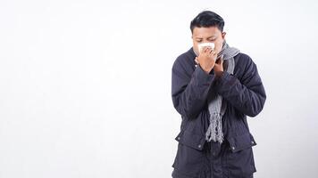 Portrait of unhealthy man wearing jacket blows his nose with tissue paper, suffering from flu isolated on white background photo