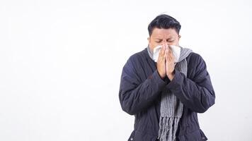 Sick man wearing jacket and wool scarf blows his nose with tissue paper, suffering from flu isolated on white background photo