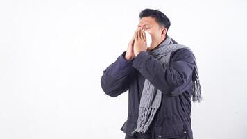 Portrait of sick man wearing jacket and wool scarf blows his nose with tissue paper, suffering from flu isolated on white background photo