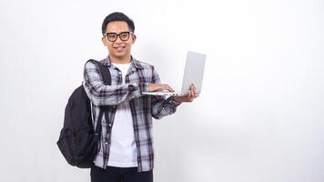 Portrait of excited young Asian male college student with a backpack and touching open laptop notebook isolated on white background photo