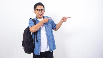 Portrait of young Asian male university student in casual outfit with backpack is presenting empty space isolated on white background photo